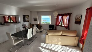 Ein Wohnzimmer mit einer Couch, Fernseher und einem Essbereich mit Stühlen und einem Tisch.