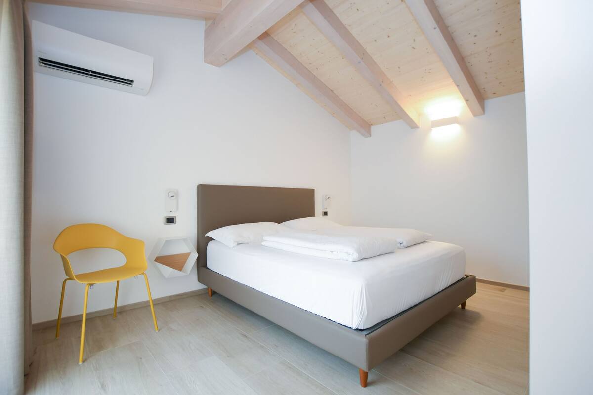 A bedroom with a bed, a chair, and an air conditioning unit.