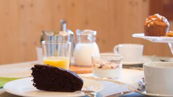 A breakfast setting with a slice of chocolate cake, a muffin, and a glass of orange juice on a table.