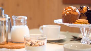 A breakfast setting with muffins, a glass of milk, and a cup on a table.