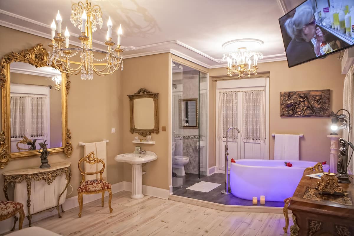 A luxurious bathroom with a large bathtub, a vanity with a mirror, and a chandelier.