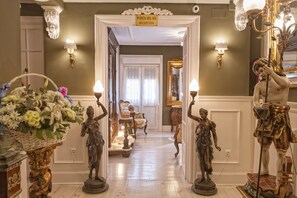 Un pasillo con recepción, apliques ornamentales y estatuas clásicas.