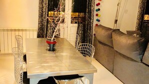 Ein Essbereich mit Tisch, Stühlen, einer dekorativen Lampe und einer Couch.