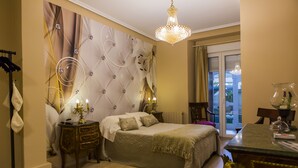 Ein Schlafzimmer mit einem großen Bett, einer Kristallleuchtre, einem Schminktisch und Blick ins Freie durch eine Glastür.