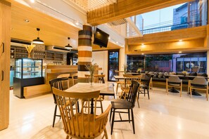 A modern restaurant interior with wooden furniture, a central pillar, and a TV mounted on the ceiling. - The Pattern Boutique Hotel (Bangkok)
