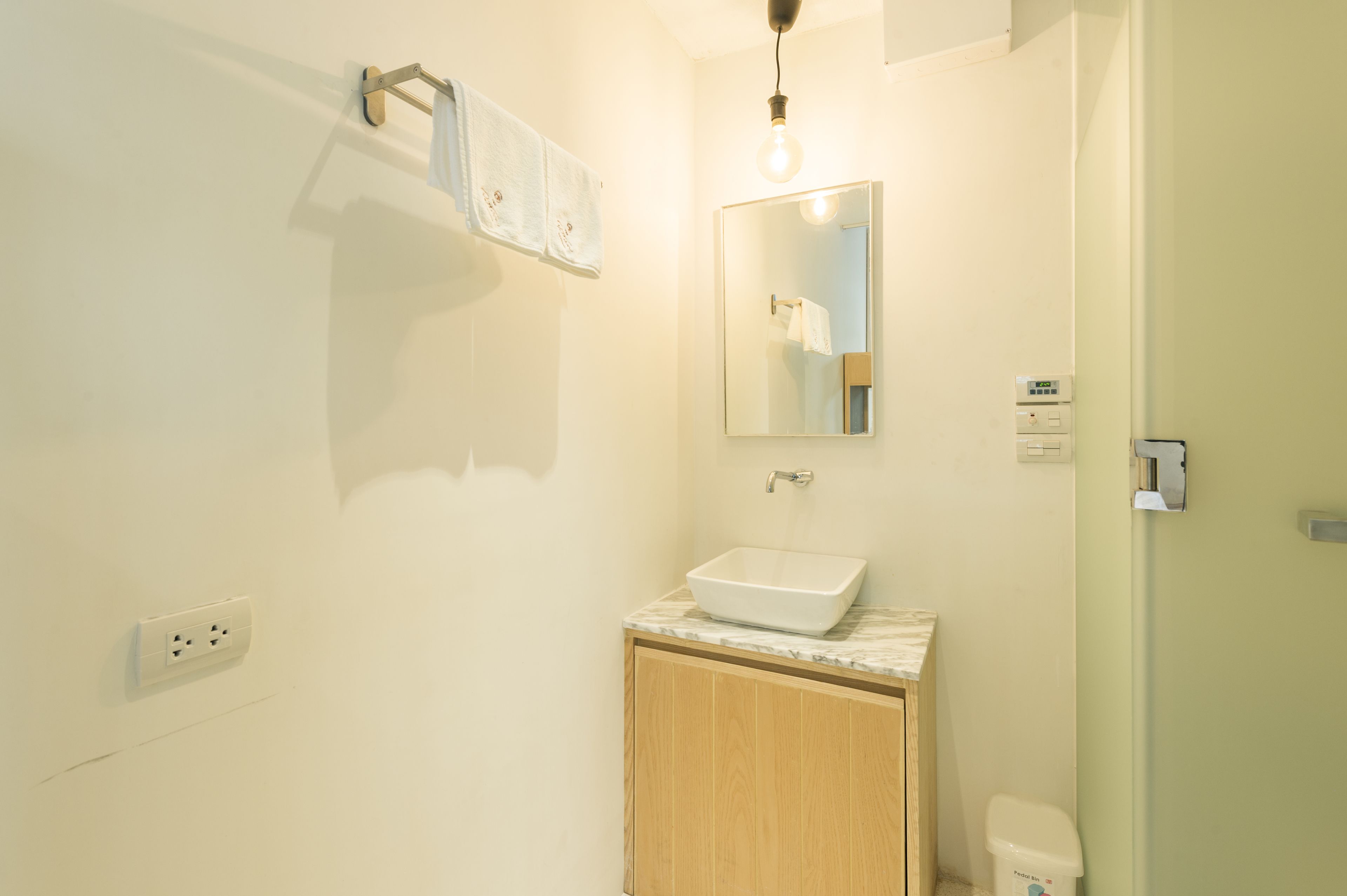 Une salle de bain avec un lavabo blanc, un meuble en bois et un miroir.