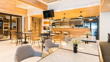 A modern cafe with wooden furniture, a bar area, and a television screen.