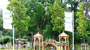 A park with wooden structures, including a water wheel and gazebos, surrounded by lush greenery. - 2 room above (45012) - Apartment 45012 and 45013 (Göhren)