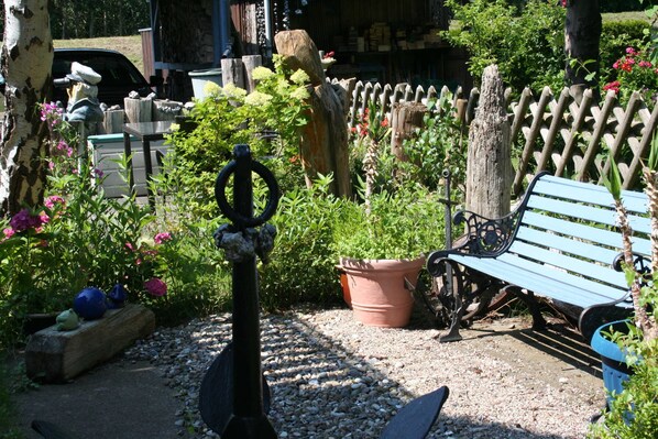 A garden with a bench, a wooden fence, and a variety of plants.