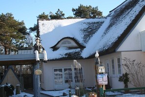 A building with a snow-covered roof, a visible window, and a sign with a number.