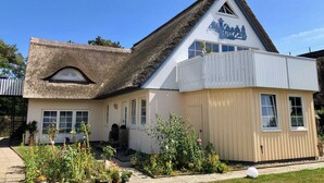 A building with a thatched roof, a white facade, and a sign indicating it is a restaurant.