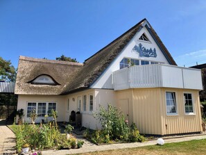 A building with a thatched roof, a white facade, and a sign indicating it is a restaurant. - On the beach, Germany (Wustrow)
