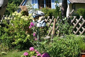 A garden with a wooden fence, a tree stump, and pink flowers.
