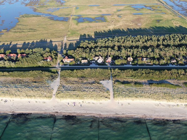 An aerial view of a coastal area with a road, houses, and a beach.