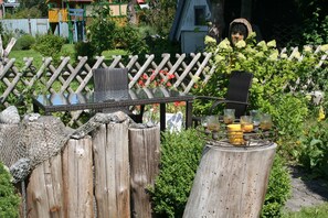 A garden setting with a wooden fence, a table with a glass top, and a rustic wooden stump.