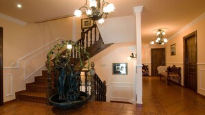 Un magnifique escalier orné d’une fontaine, de rampes en bois et d’un lustre.