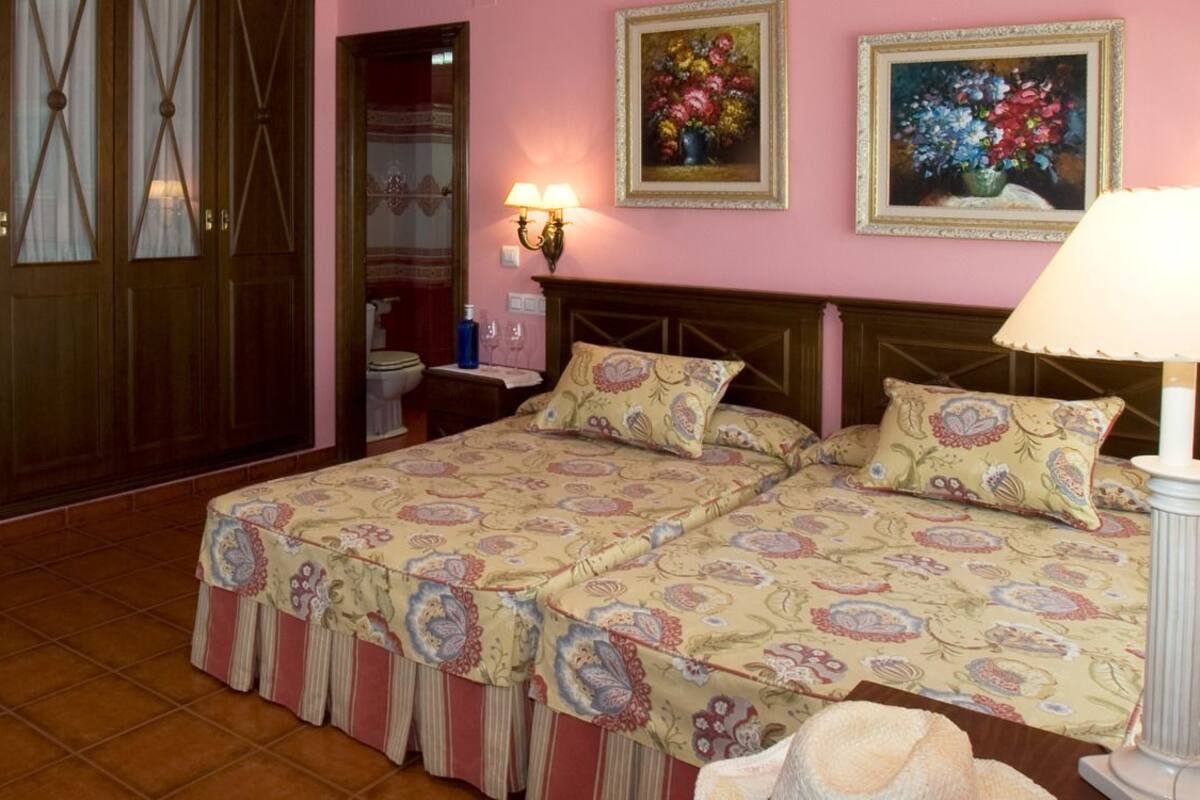 A bedroom with a bed, bedside table, lamp, and a mirror.