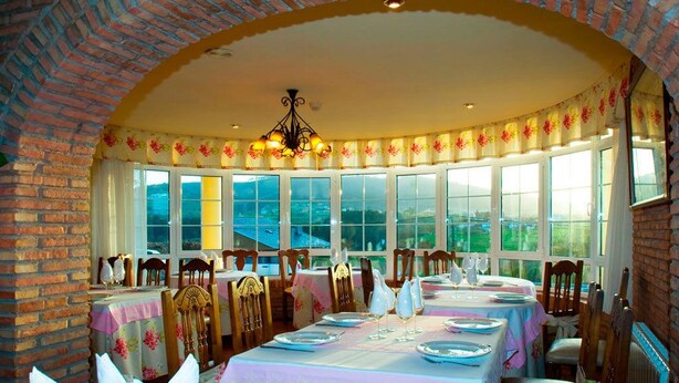 Un espace repas agrémenté d’arches en briques, de grandes fenêtres et de tables dressées pour le repas.