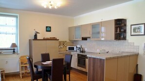 A compact kitchen with a dining area, wooden cabinets, a microwave, and a small island.