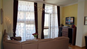 A living room with a sofa, a television, and a dining area with a table and chairs.