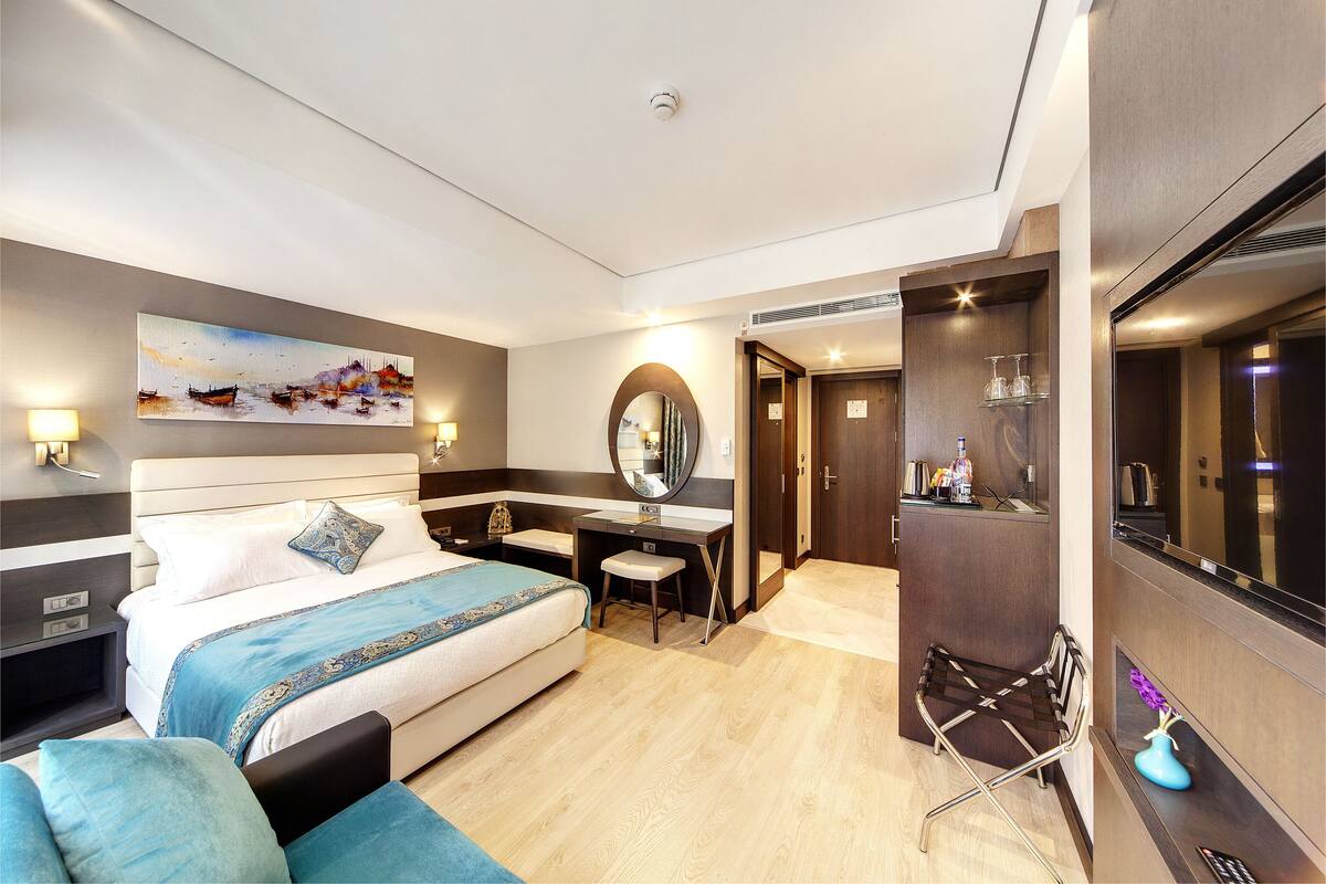 A modern hotel room with a bed, desk, and seating area.