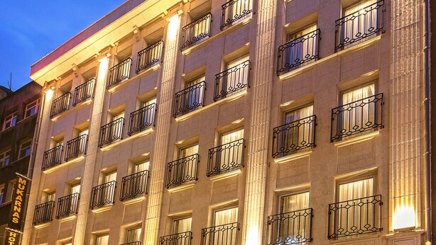 Hotel de diversos pisos amb una entrada imponent, grans finestres i una escala que condueix a l'entrada.