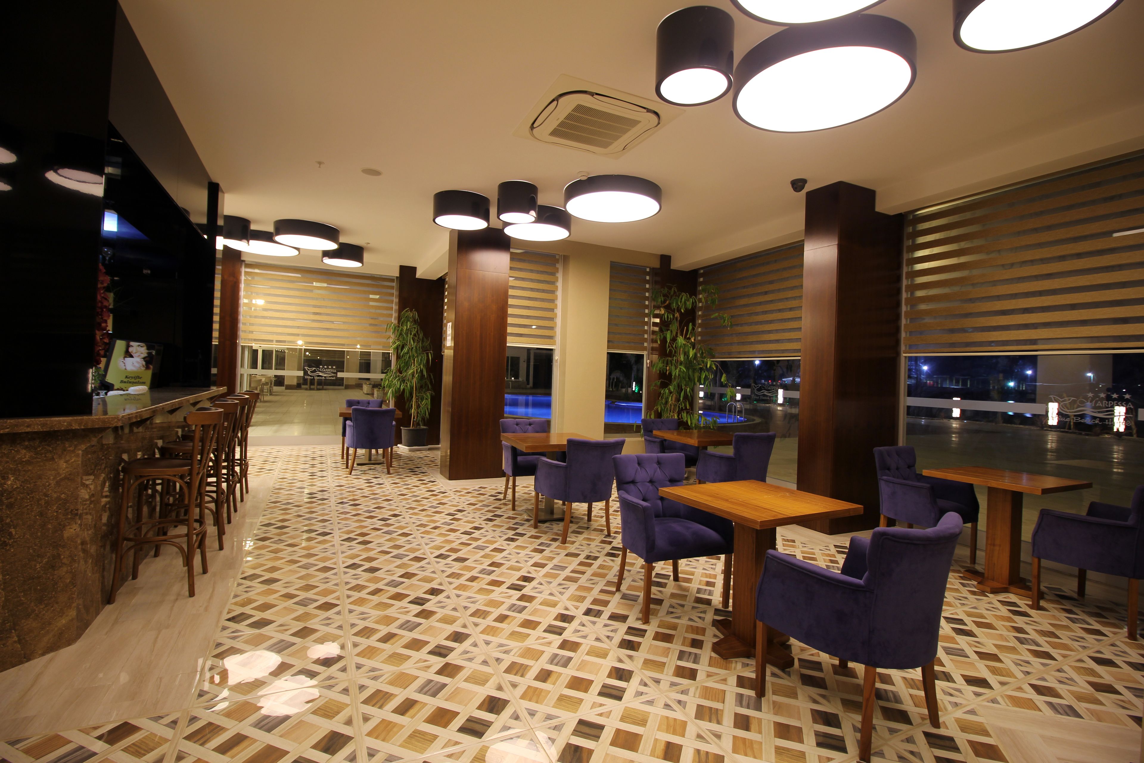 A restaurant with a patterned tile floor, wooden tables and chairs, and pendant lighting.