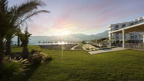 Un hotel con zona de piscina, mobiliario exterior y vistas al mar y a las montañas.