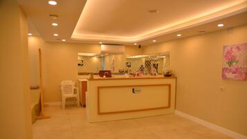 A reception area with a reception desk, a small seating area, and a wall-mounted mirror.