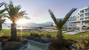 Un resort con piscina, palmeras y vistas al mar y a las montañas.