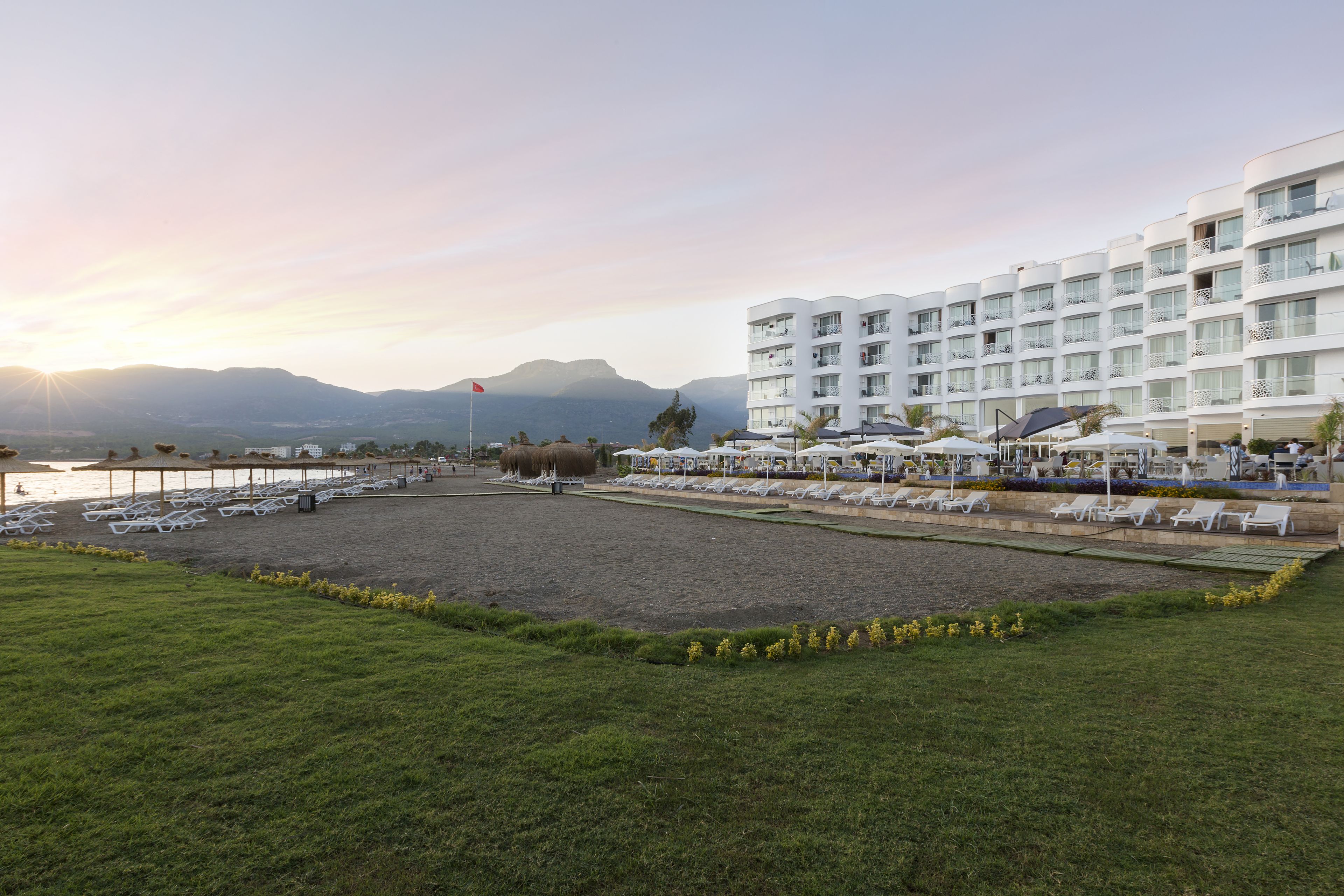 Un hotel con area piscina, lettini e vista sulle montagne.