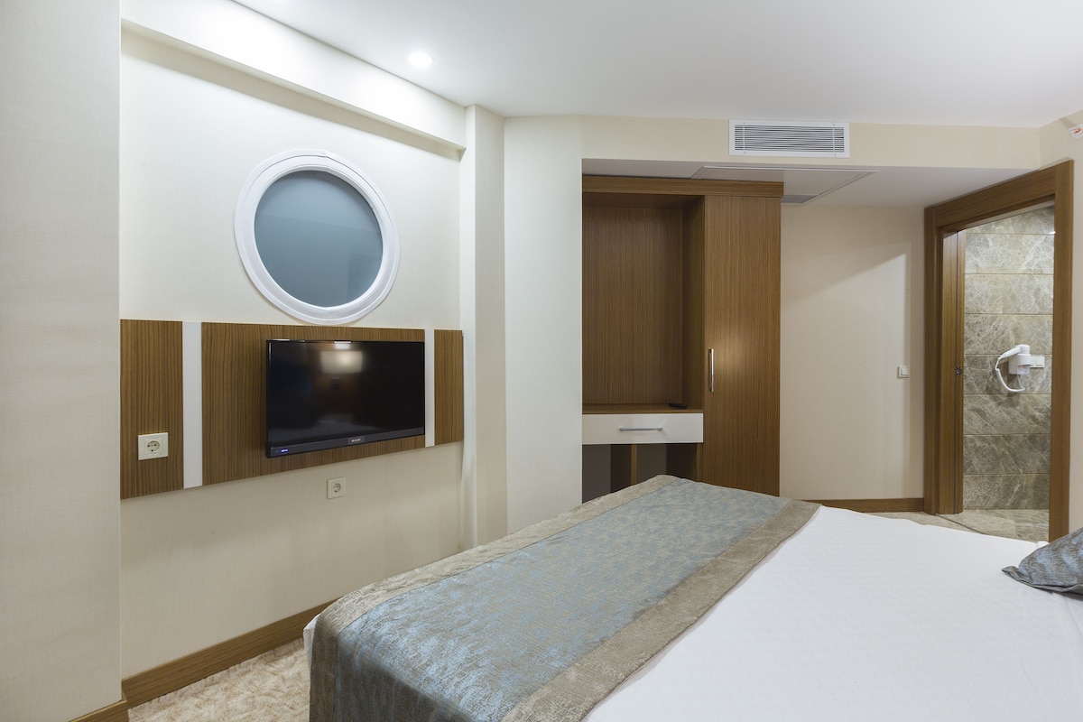 Ein Hotelzimmer mit Bett, Fernseher, Spiegel, Bad und Kleiderschrank.