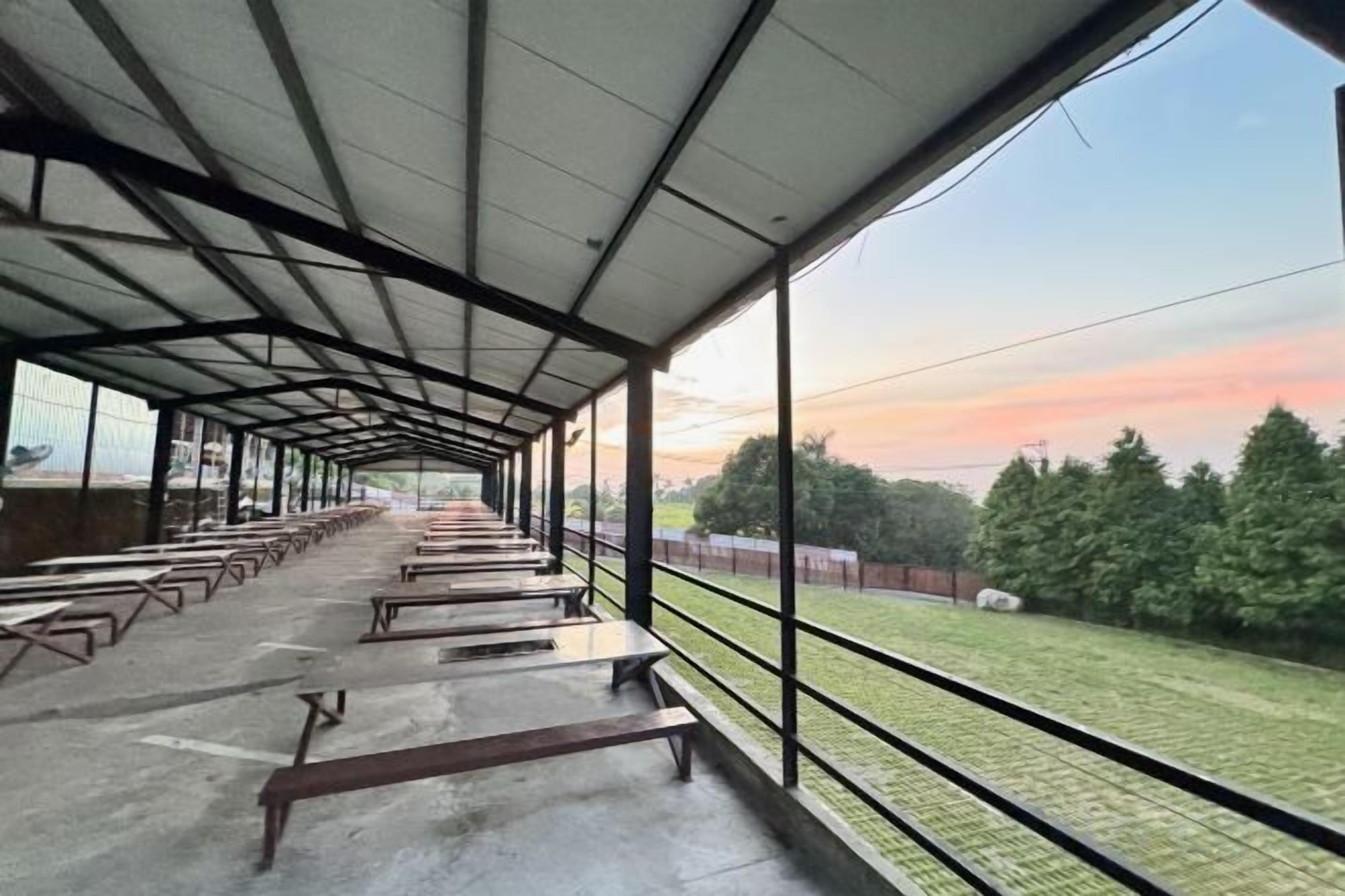 A covered outdoor area with benches and a view of a grassy field.