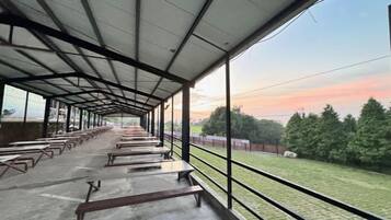 A covered outdoor area with benches and a view of a grassy field.