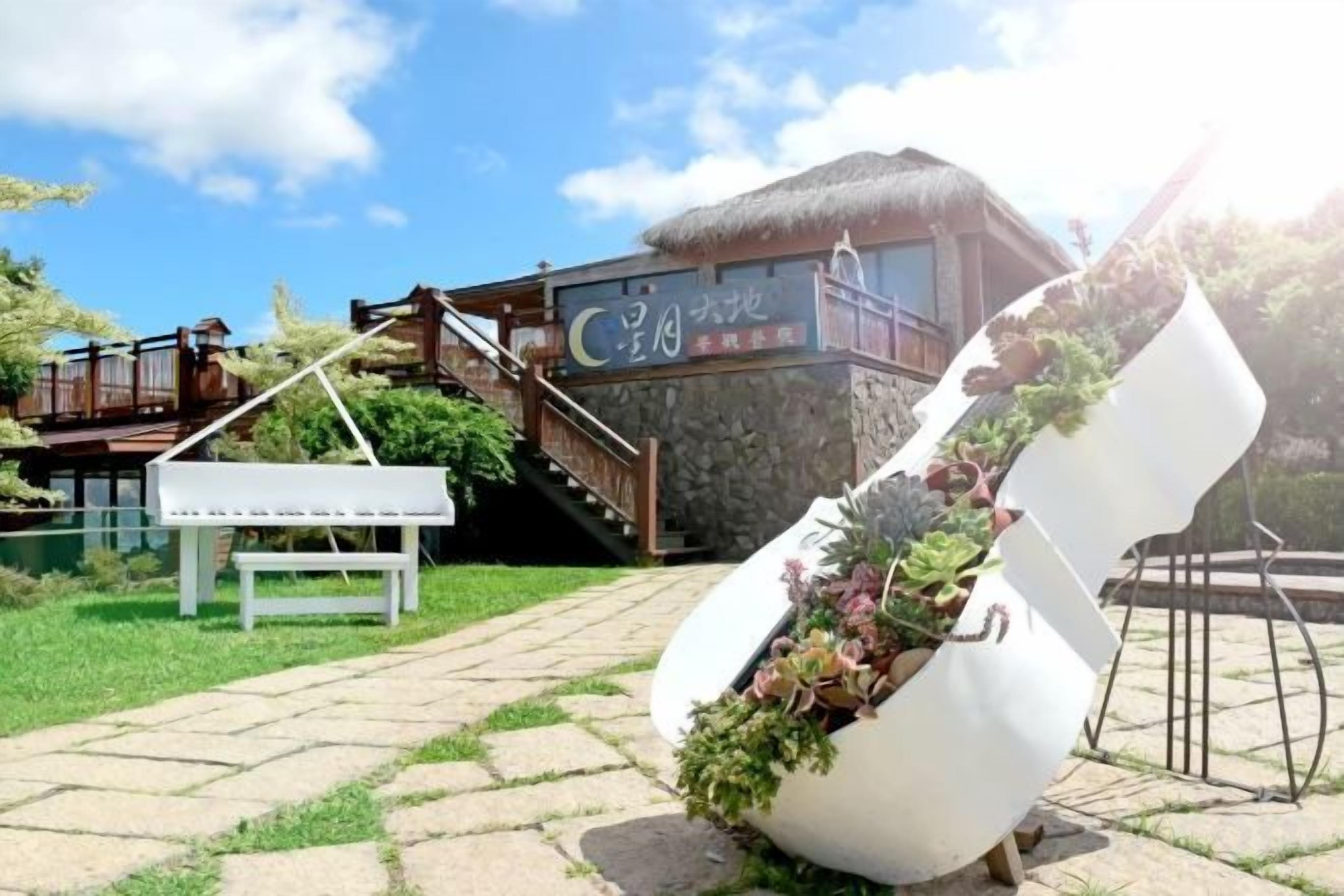 Een gebouw met rieten dak, een houten terras en een trap naar een balkon.