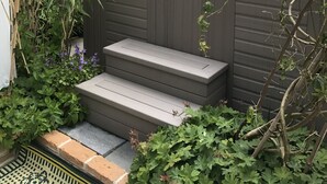 Ett bubbelbad i en frodig trädgård, med trappsteg som leder upp till det.