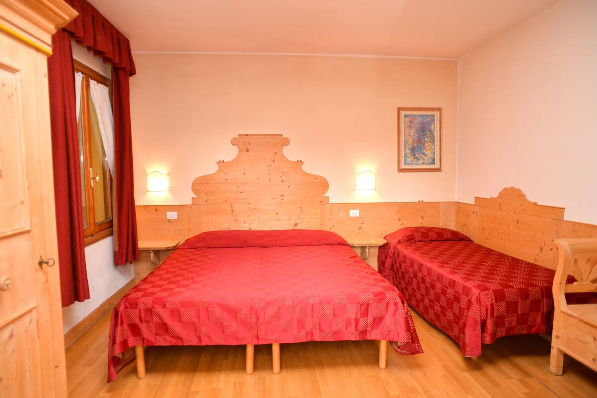 A room with two wooden beds, a wooden wardrobe, and a painting on the wall.