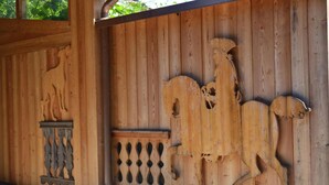 A wooden fence with carved horse figures and a decorative panel. - Albergo Da Gildo (Follina)