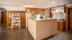 A reception area with a wooden counter, a glass display case with glasses, and a card rack with brochures. - Hotel Rotes Kreuz (Arbon)