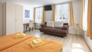 A hotel room with two beds, a sofa, a desk, and a TV. - Hotel Rotes Kreuz (Arbon)
