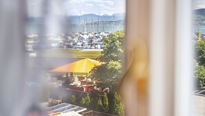 A marina with boats docked, a yellow umbrella, and a view of distant mountains. - Hotel Rotes Kreuz (Arbon)