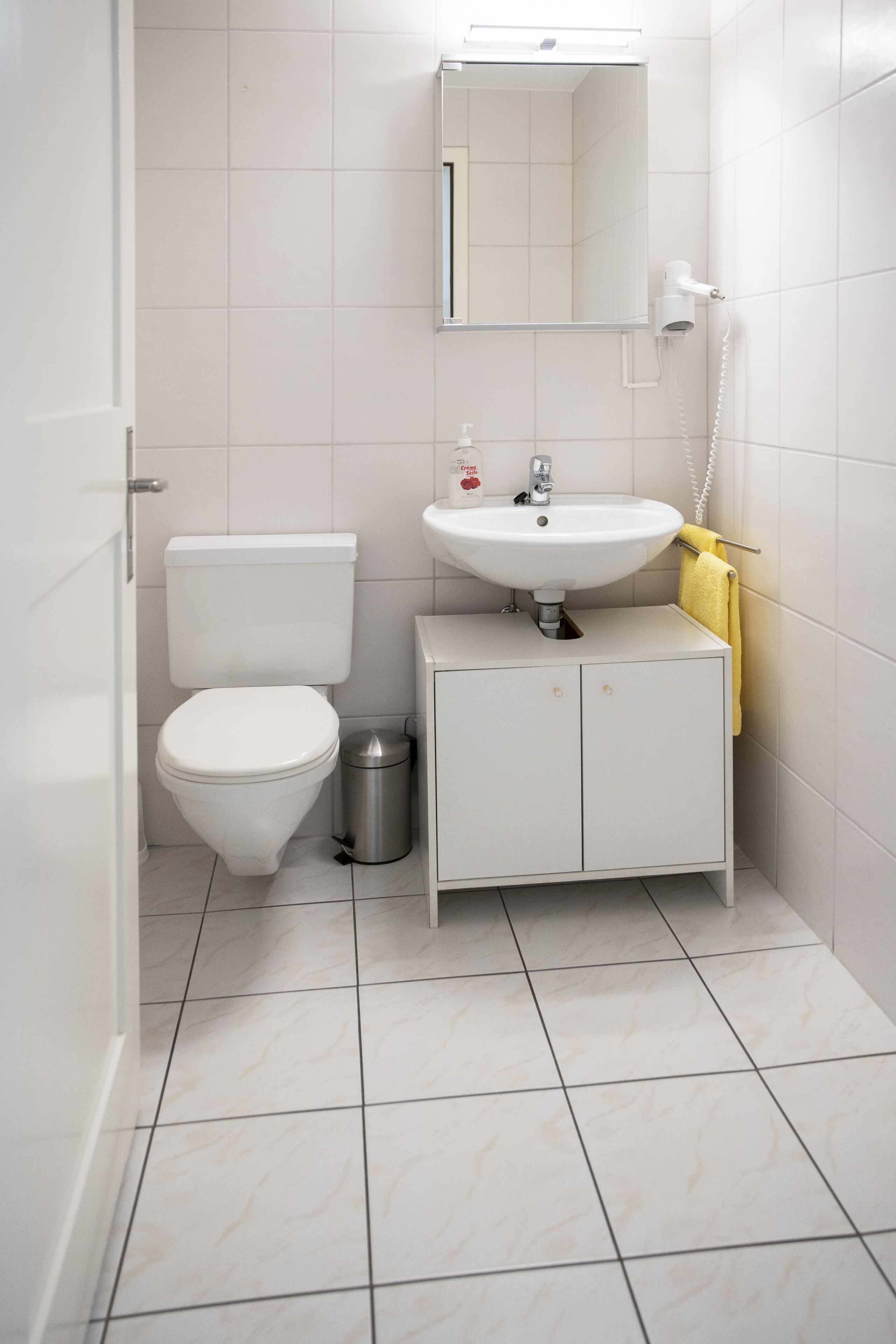 Une petite salle de bain propre, équipée de toilettes, d’un lavabo et d’un miroir.
