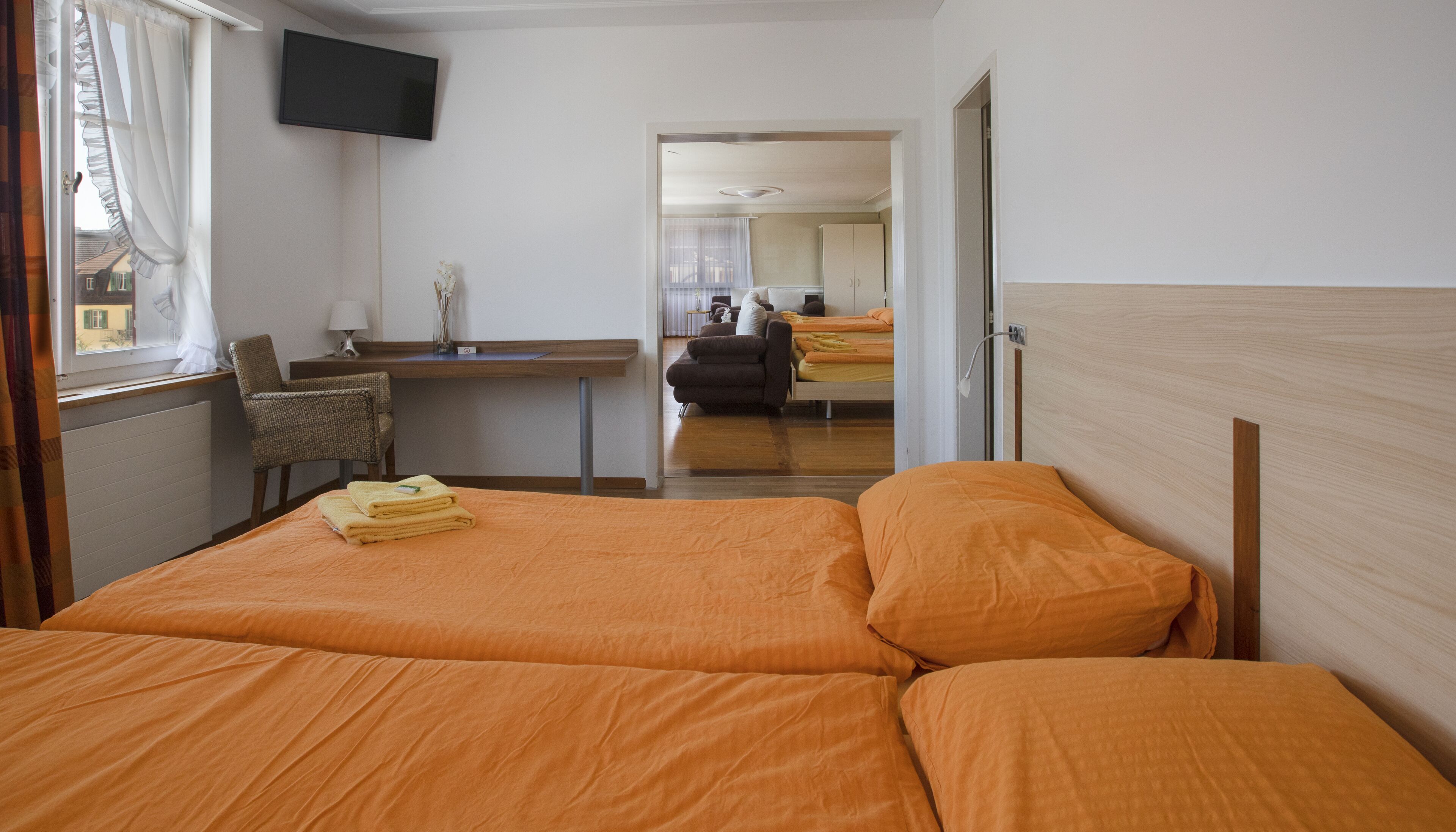 A hotel room with a bed, a desk, a chair, and a television.