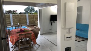 A dining area with a table and chairs, a pool, and a TV in the background.