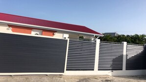 A modern building with a red roof, a grey facade, and a white fence.