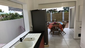 A kitchen with a gas stove, two sinks, and a refrigerator. There is a dining area with a table and chairs, and a view of the outdoors.