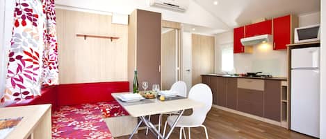Una cocina moderna con armarios rojos, una mesa de comedor con sillas y un banco empotrado con cojín floral.