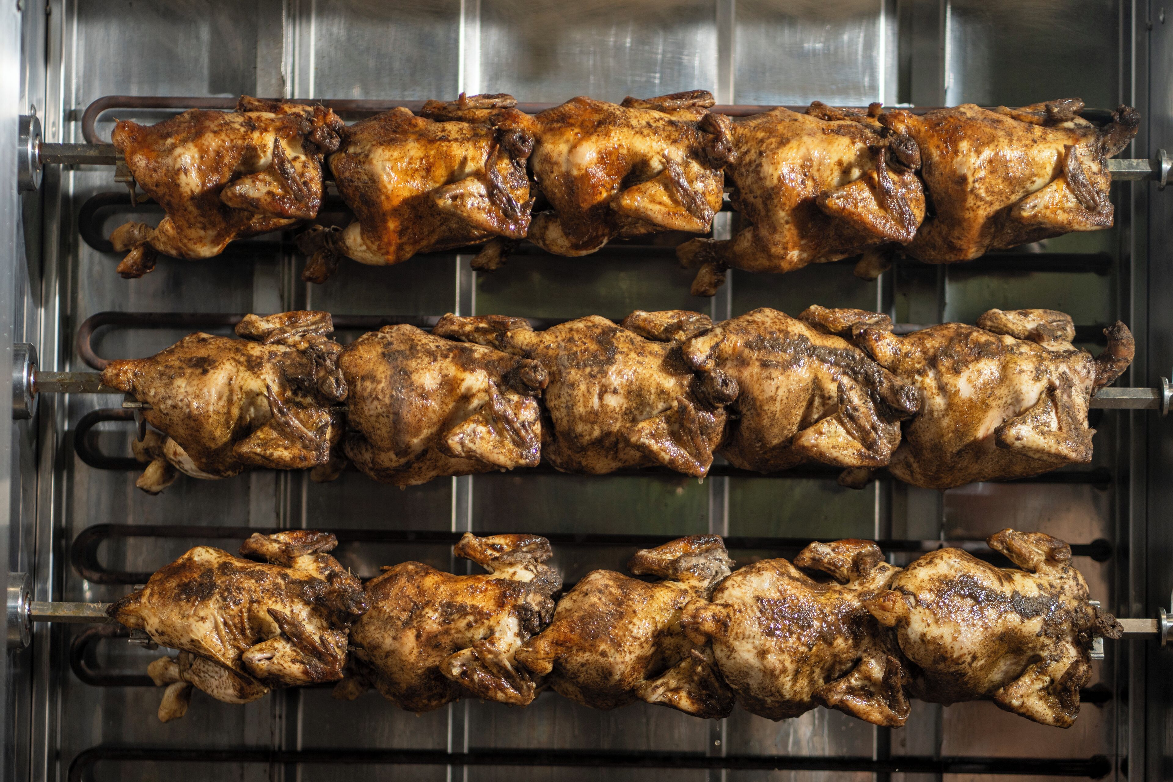 A commercial kitchen with multiple rows of hanging poultry.