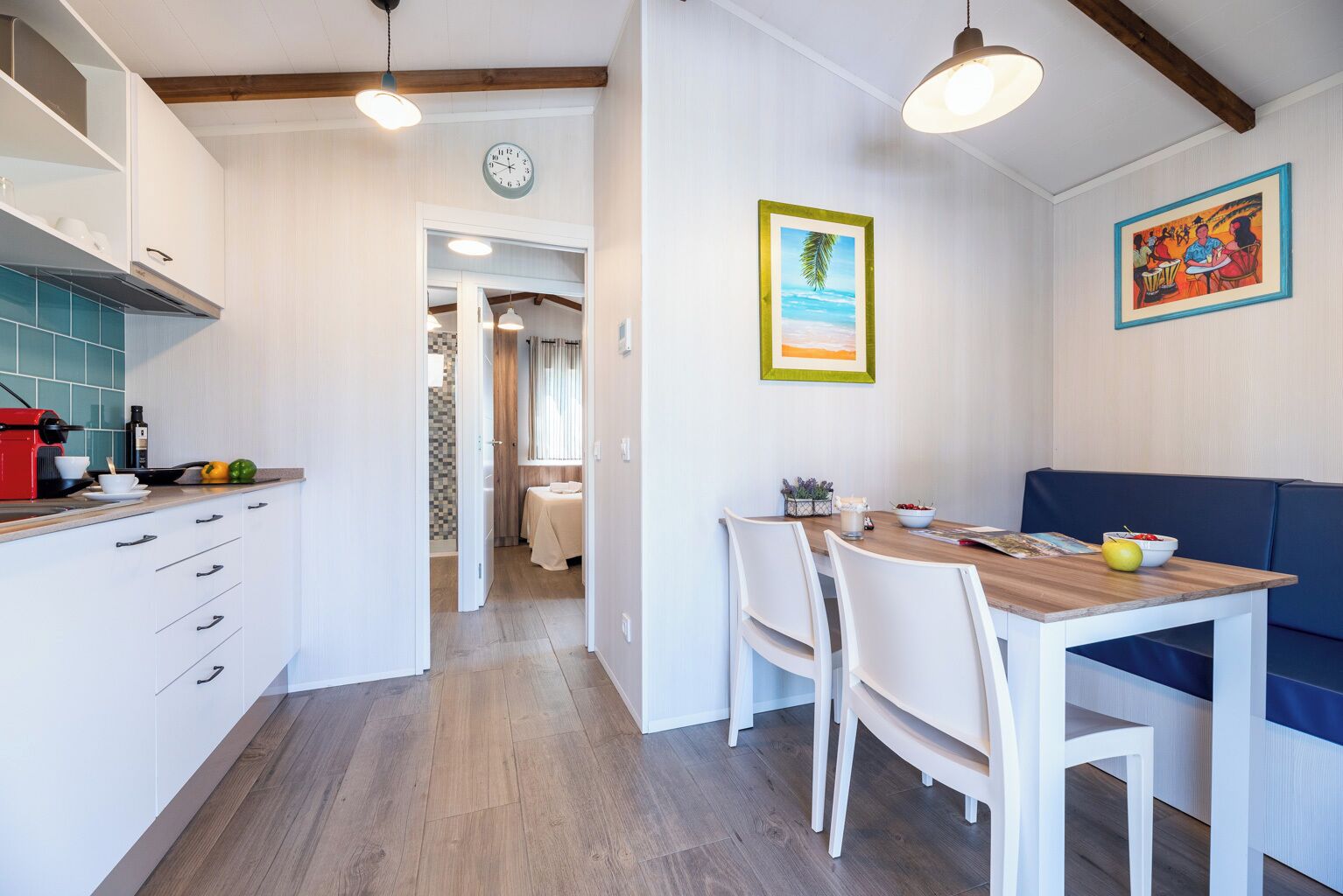 A modern kitchen with white cabinetry, a wooden dining table, and a blue sofa.