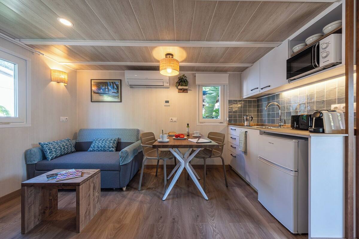 Ein kompakter Wohnbereich mit Sofa, Esstisch und Küchenzeile.